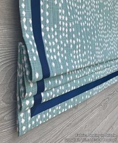 a close up of a blue and white curtain with polka dots on the fabric, attached to a wooden wall