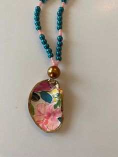 Necklace handmade with a mixture of glass beads and seed beads with an oyster attached. Oyster shell decoupaged in a bright floral print. The rim of the shell is painted in gold leaf paint to accentuate its wonderful uniqueness. Beads are assembled on an elastic strand for easy on and off. This is an amazing statement piece! Color: Gold, Turquoise, Pink, Bright floral Length: approx 15.5" Care Instructions: Not recommended for the necklace to get wet as it will wear down elastic Avoid over stretching Keep out of sunlight as it may fade Note:  Items are made to order Order is for ONE necklace. I use only natural light and I do not use any filters on my pictures. Screen or computer settings may possibly distort colors. Not recommended for kids  This shop assumes no responsibility for jewelry Bohemian Shell With Colorful Beads For Gift, Colorful Beads Shell Necklace For Gifts, Shell-shaped Colorful Bead Necklaces For Gifts, Multicolor Shell Necklace As A Gift, Colorful Shell Bead Necklaces For Gifts, Beaded Multicolor Shell As Gift, Multicolor Beaded Shell As A Gift, Multicolor Beaded Shell As Gift, Handmade Multicolor Shell As A Gift