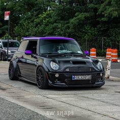 a black car with purple stripes parked on the street