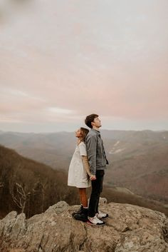 a man and woman standing on top of a mountain