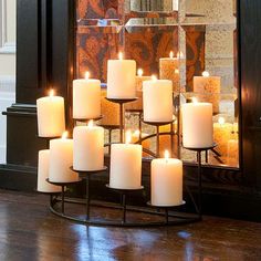 a bunch of lit candles sitting on top of a stand in front of a mirror