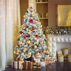 a white christmas tree with gold and red ornaments in front of a fireplace mantel