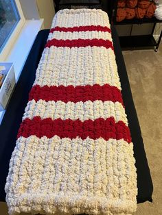 a crocheted blanket sitting on top of a black table next to a window