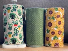 three rolls of toilet paper sitting next to each other on a shelf with potted plants