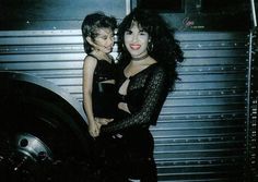 a woman and child standing next to each other in front of a metal structure with a door behind them