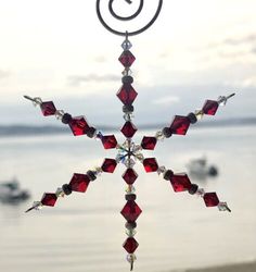 a snowflake hanging from the side of a window next to a body of water