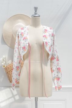 A cute and unique cardigan, the vintage-inspired Coquette bolero-style sweater features long sleeves, a lovely pink rose print, and a blush pink bow-style ribbon closure. . Details: S: Bust 38", Length 16" M: Bust 40", Length 17" L: Bust 42", Length 18" Length Measured from Shoulder Material: 50% Nylon, 20% Wool, 15% Polyester, 15% Acrylic Hand Wash Cold/Flat Dry/Dry Clean Imported Long Sleeve Pink Shrug For Spring, Pink Long Sleeve Shrug For Spring, Spring Cotton Fitted Shrug, Spring Fitted Cotton Shrug, Fitted Cotton Spring Shrug, Fitted Cotton Shrug For Spring, Bolero Style, Unique Cardigan, Bolero Sweater