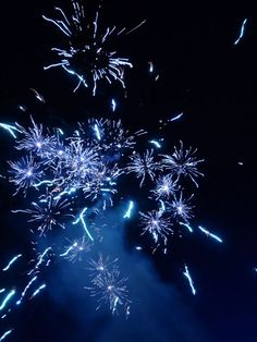 fireworks are lit up in the night sky with blue and white lights coming out from them