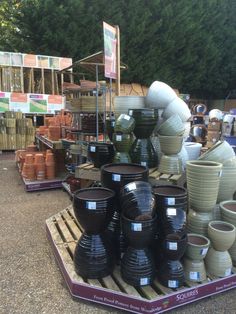 many pots are stacked up on a pallet in front of some other items for sale