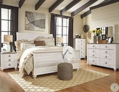 a bedroom with white furniture and wood floors