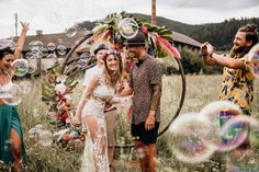 a group of people standing in a field with soap bubbles floating around them and one person taking a photo