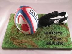 a birthday cake with a rugby ball and boot on it's green grass mat