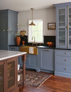 a kitchen with blue cabinets and wood flooring is pictured in this image, the sink has gold faucets on it