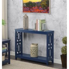 a blue console table with two vases on it and a painting in the background