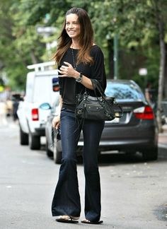 a woman is walking down the street with her cell phone in her hand and smiling