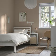 a bed room with a neatly made bed next to a window and a rug on the floor