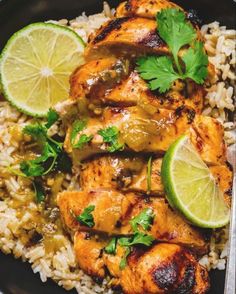 chicken and rice with cilantro garnishes on a black platter