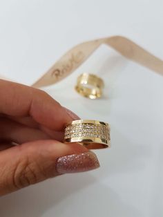 a woman's hand is holding two gold rings with small diamonds on the sides