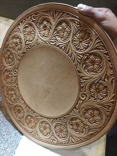 a person holding a decorative bowl on top of a table