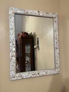 a mirror that is on the side of a wall next to a shelf with flowers