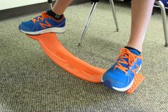 a person wearing blue and orange shoes stepping on an orange shoe arch while sitting in a chair