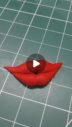 a fake red lip sitting on top of a tiled floor