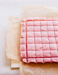 a piece of pink cake sitting on top of parchment paper