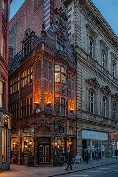 an old building is lit up at night in the middle of a city with tall buildings