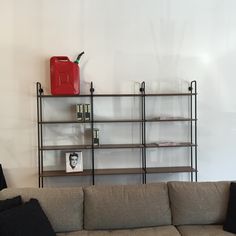 a living room filled with furniture and a red container on top of a book shelf