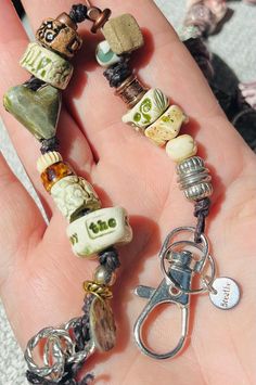 a hand holding a bunch of charms on it's thumb and a pair of scissors