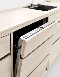 a kitchen with a sink, dishwasher and wooden cabinet doors that are open