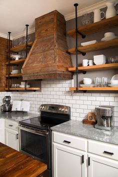 a stove top oven sitting inside of a kitchen next to wooden shelves filled with dishes