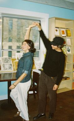 two people standing in front of a window with their arms up and one person reaching for something