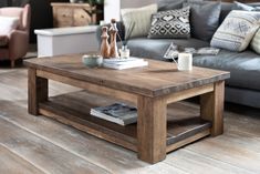 a wooden table sitting on top of a hard wood floor next to a gray couch