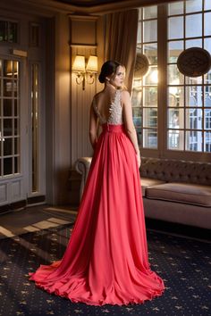 a woman in a long red dress looking out the window