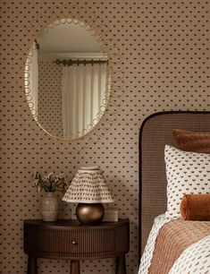 a bed room with a neatly made bed and a round mirror