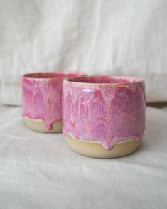 two small pink bowls sitting on top of a white tablecloth covered bedding area