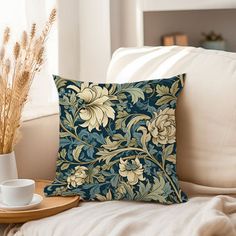 a blue and yellow pillow sitting on top of a white couch next to a cup