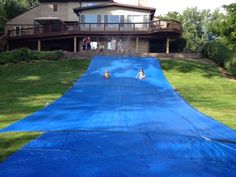 people are playing on an inflatable water slide at the back of a house