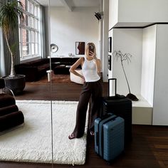 a woman is sitting on the floor with her luggage and taking a selfie in an apartment