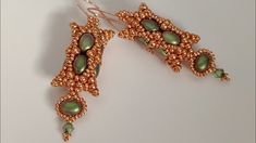 a pair of gold and green beaded earrings