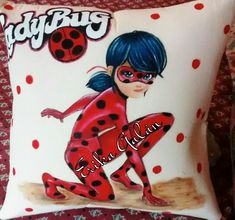 a ladybug pillow on a bed with red and black polka dots