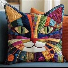 a colorful cat pillow sitting on top of a blue couch