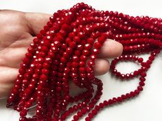 a hand is holding some red beads