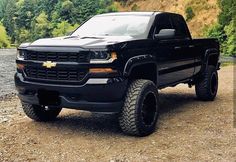 a black truck parked on top of a dirt field