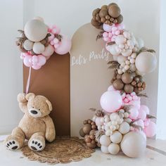 a teddy bear sitting next to a balloon arch