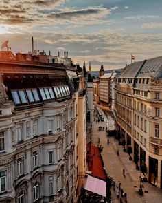 an aerial view of buildings and people walking on the sidewalk in front of them at sunset