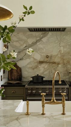 a kitchen with marble counter tops and gold faucets on the sink, next to an oven