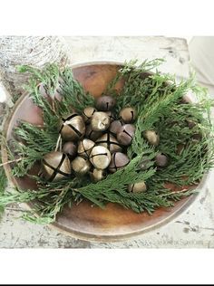 a bowl filled with lots of nuts and greenery on top of a wooden table