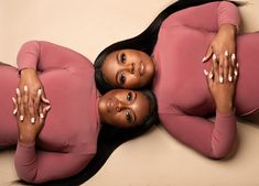 two women in pink bodysuits laying down on the floor with their arms around each other